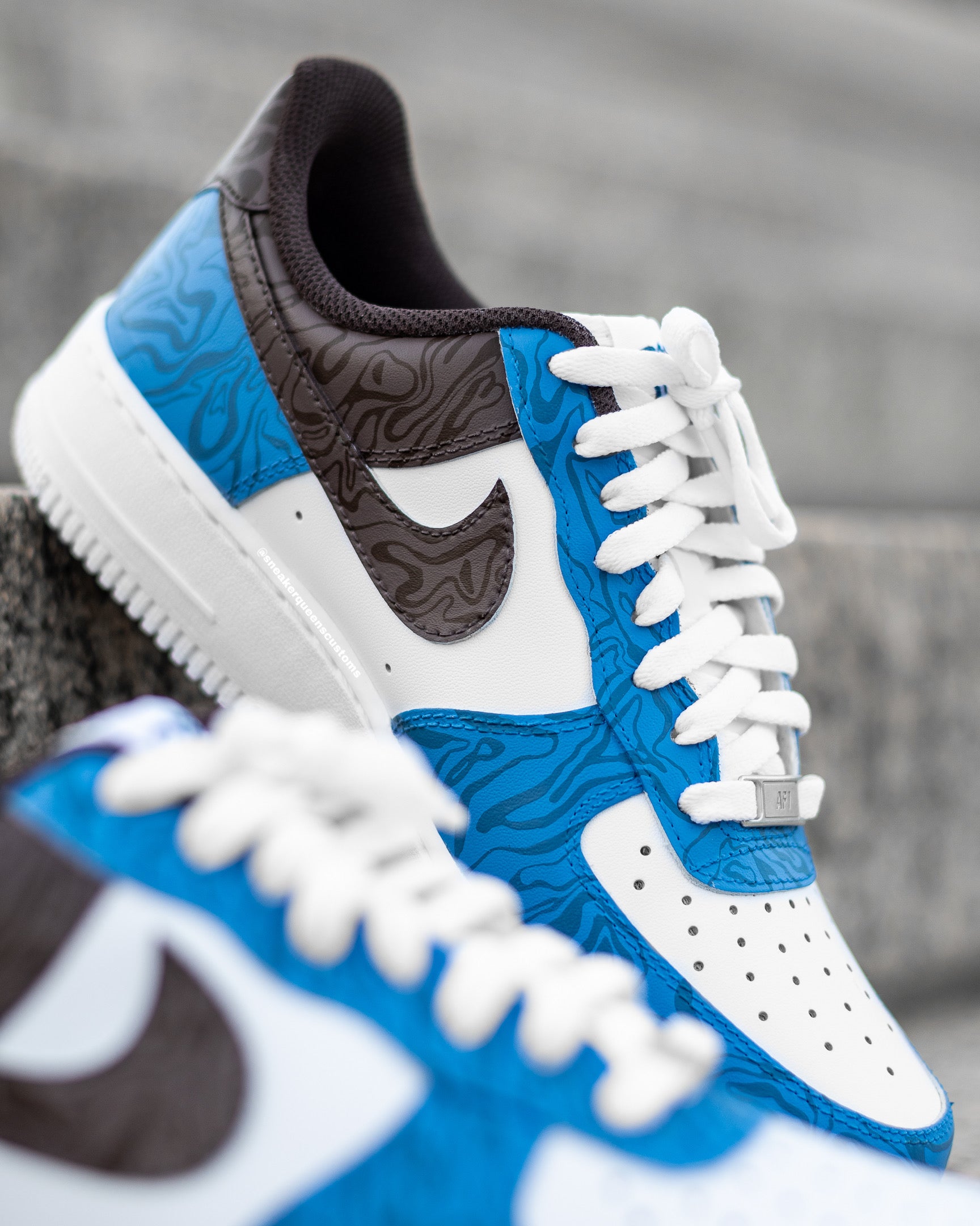 Custom Nike Air Force 1 sneakers featuring Sneaker Queens Customs’ signature Anxiety Swirls in a bold blue and brown color way, with intricate patterns on white leather.